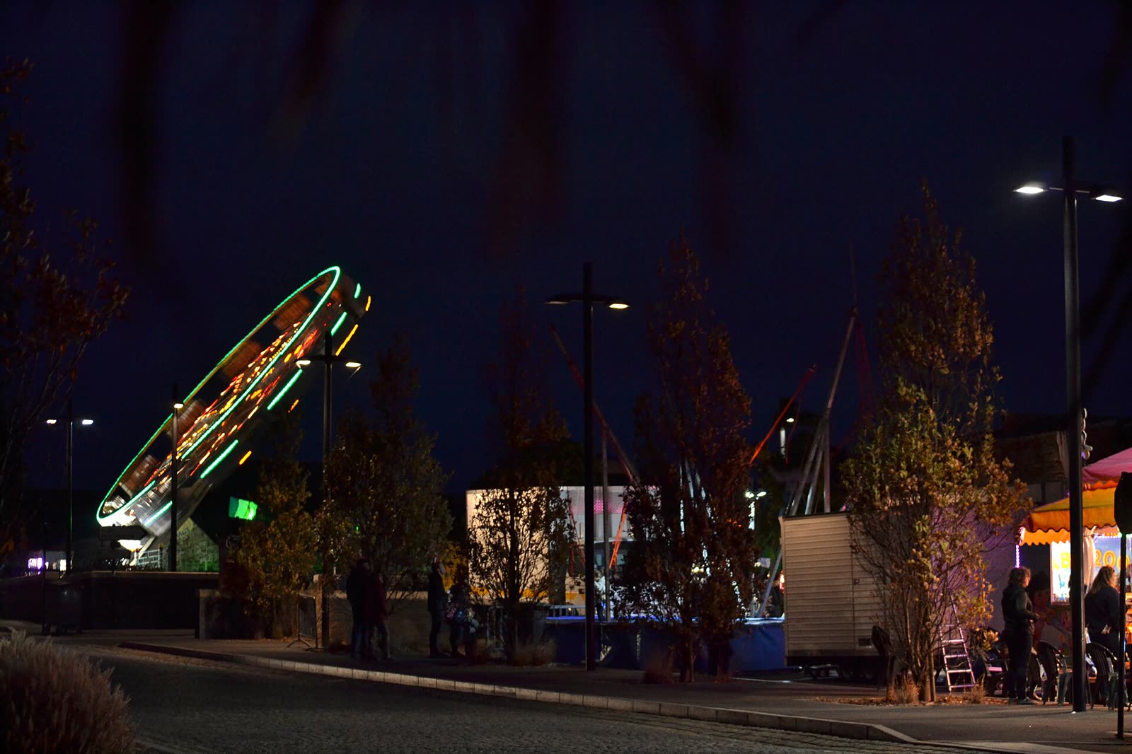 Manèges et stands éclairés d'une fête foraine, la nuit